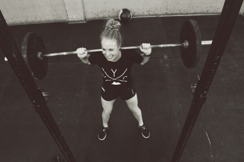 girl in red shirt and white panty holding red barbell